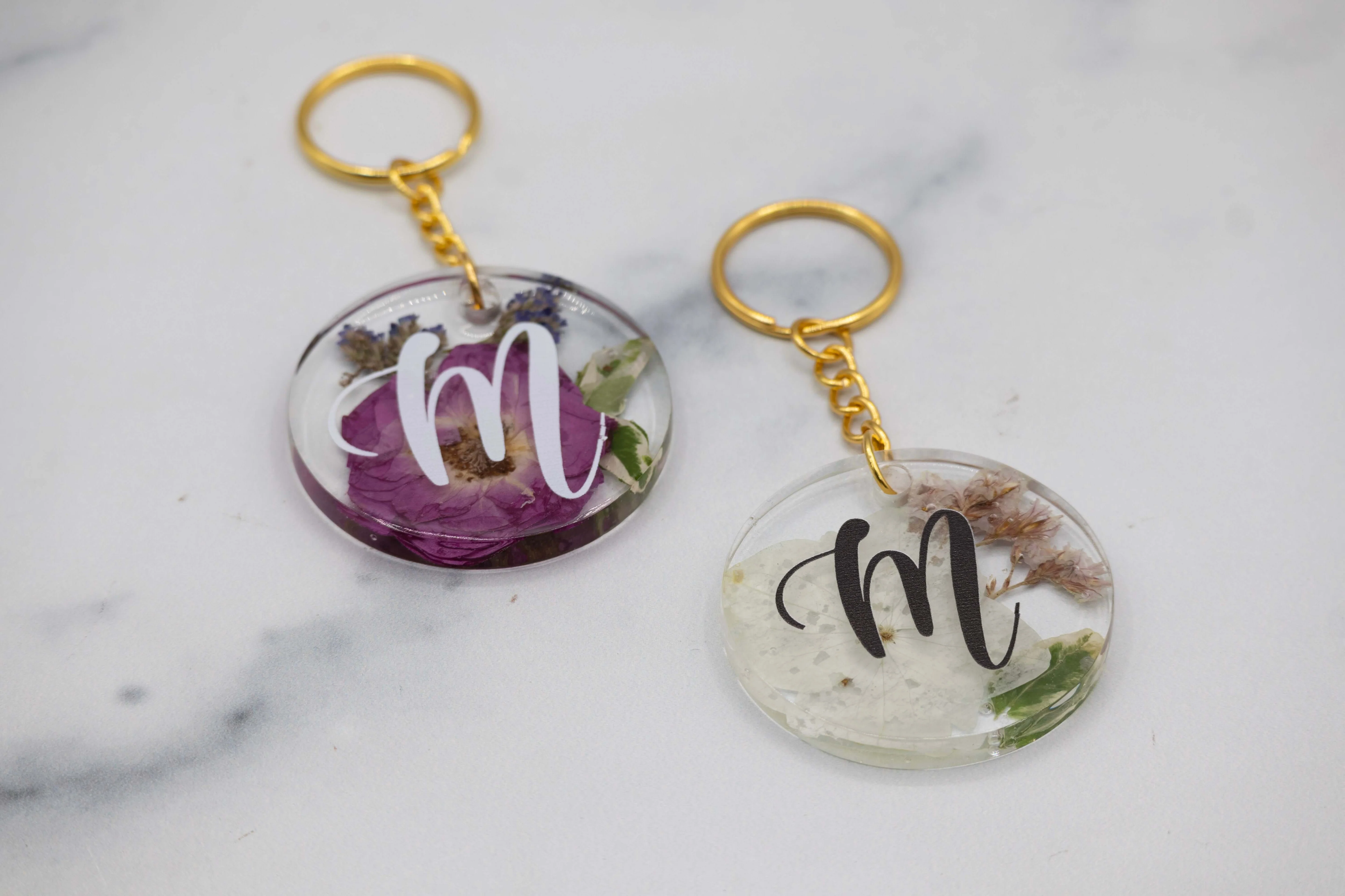 A finished clear resin keychain on a wooden table with subtle gold glitter inside and a metal keyring attached