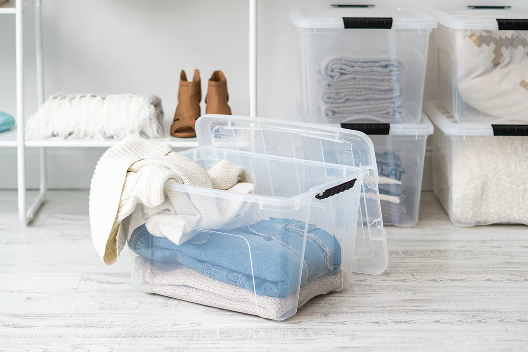 A photo of a resin coaster mold tray on a table covered by an upside-down clear plastic storage bin to protect it while curing