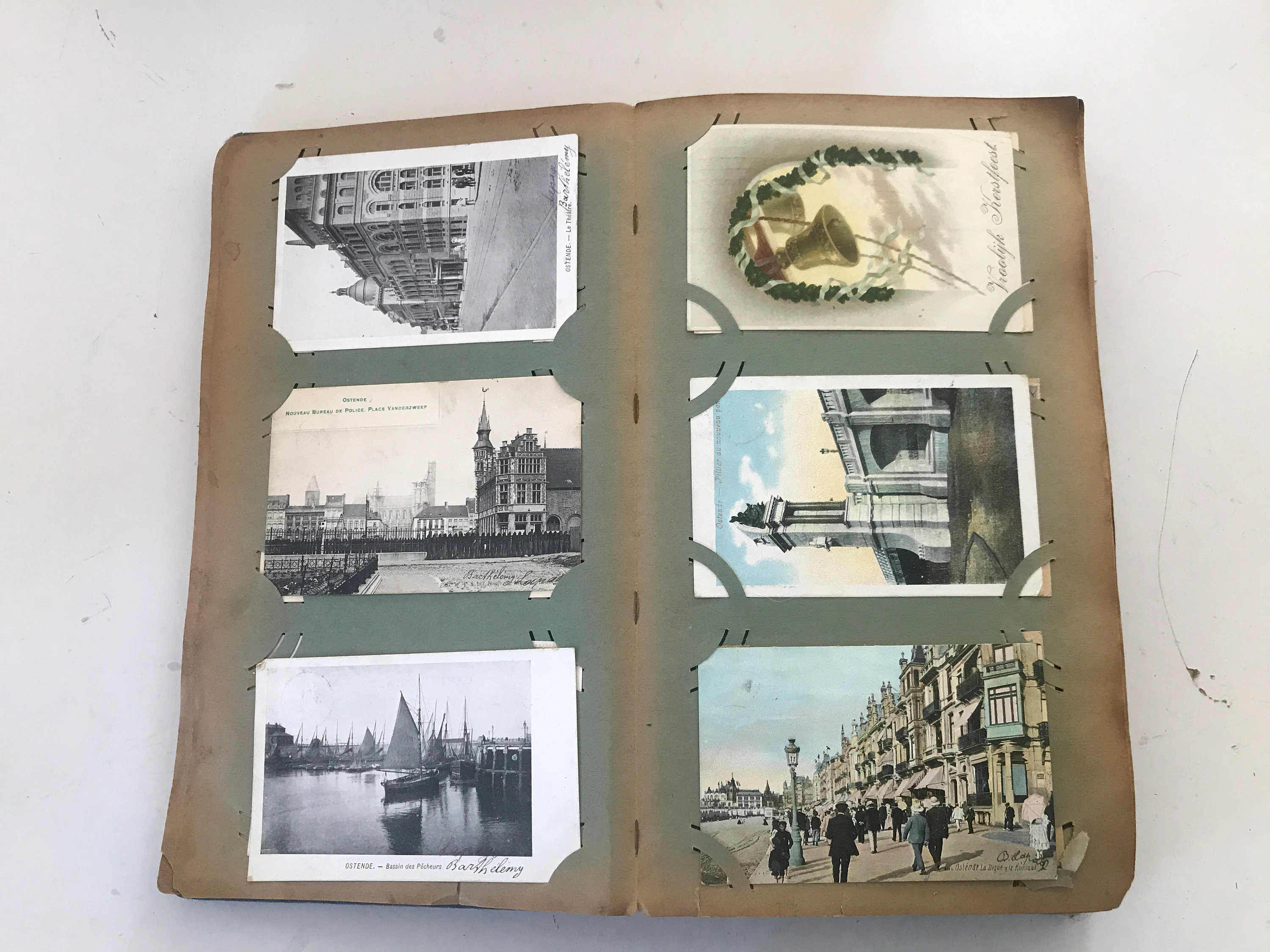 A small stack of vintage postcards and a simple binder with clear sleeve pages on a wooden table in natural window light