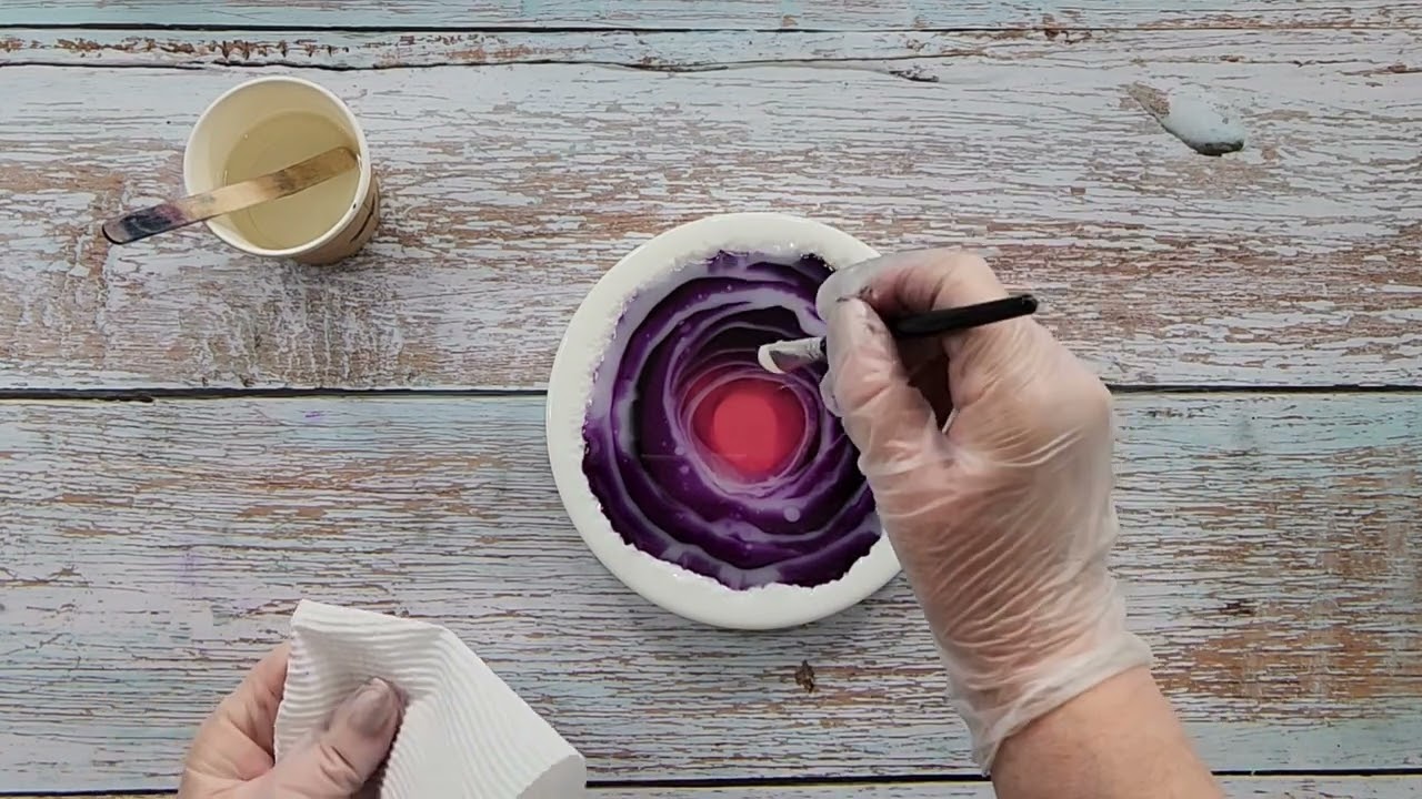 Resin is poured into a round silicone coaster mold with two colors forming a gentle swirl pattern