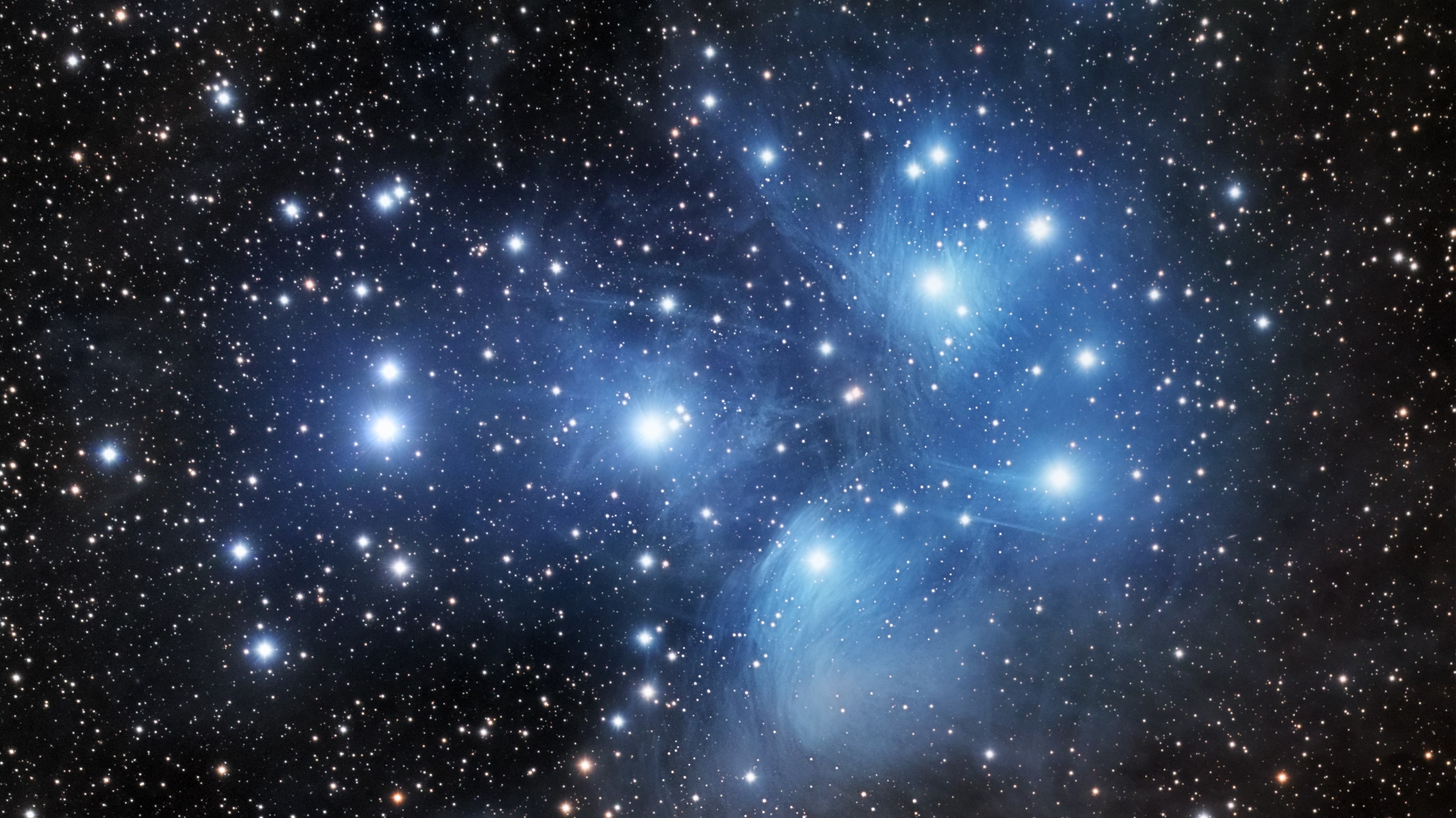 The Pleiades star cluster seen through a telescope eyepiece, with bright blue-white stars scattered across a wide black sky